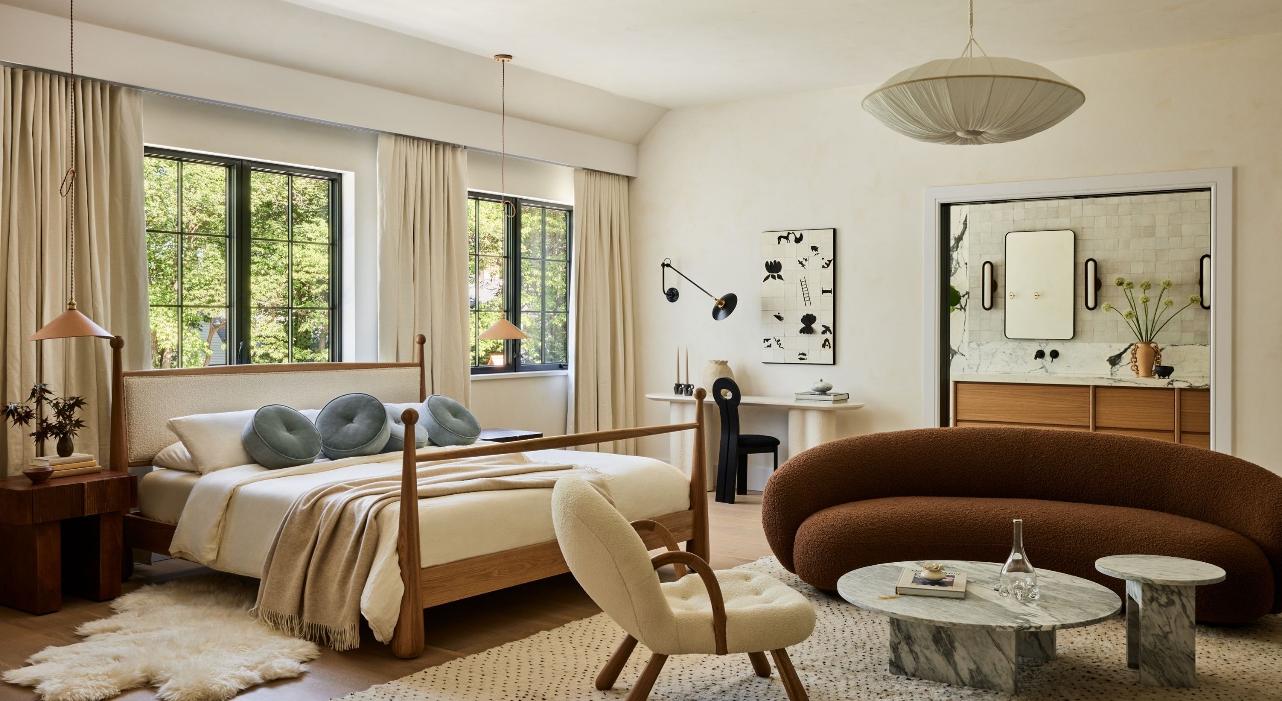 Interior shots depicting an apartment decorated with sculptural furnishings in earthy tones, framed artworks, marble and wood countertops, all bathing in natural light.