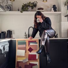 Woman drinking from a mug sitting on kitchen countertop