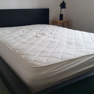 The Woolroom Deluxe Washable Wool Mattress Protector being tested on a mattress in a bedroom