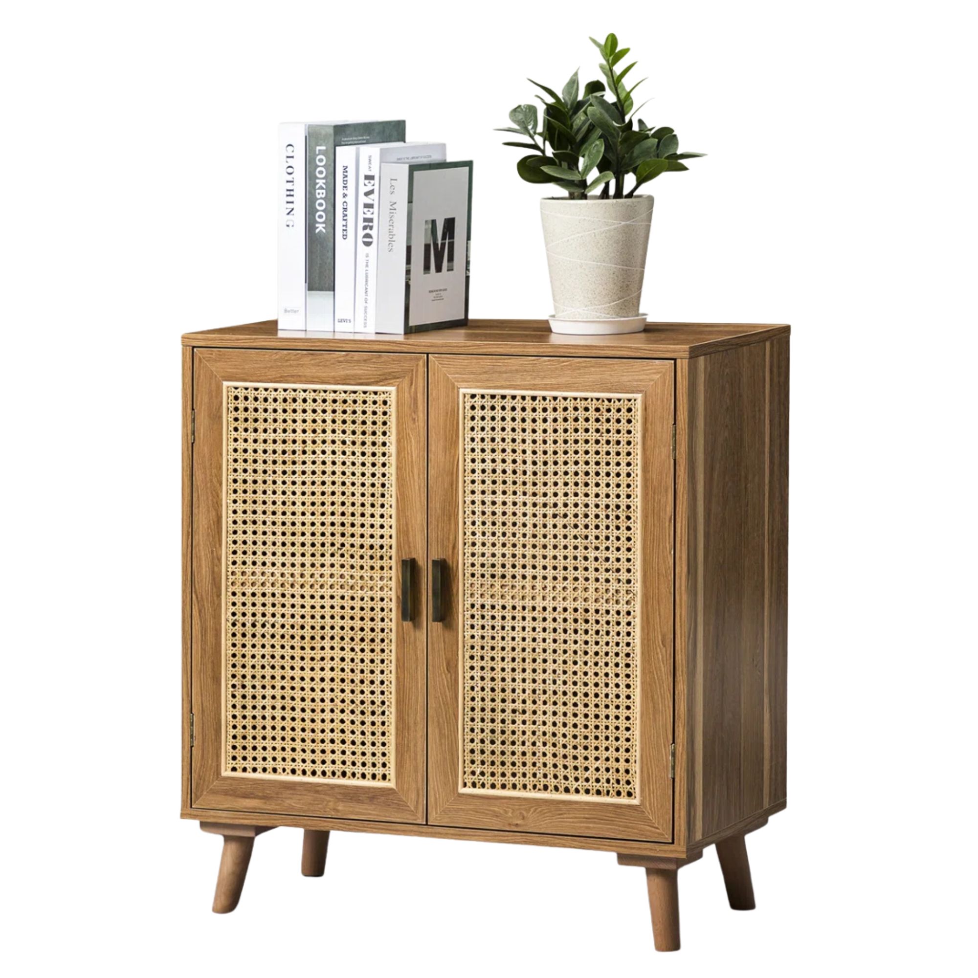 A brown wood and wicker rattan storage cabinet with white coffee table books and a white vase with green plant on top.