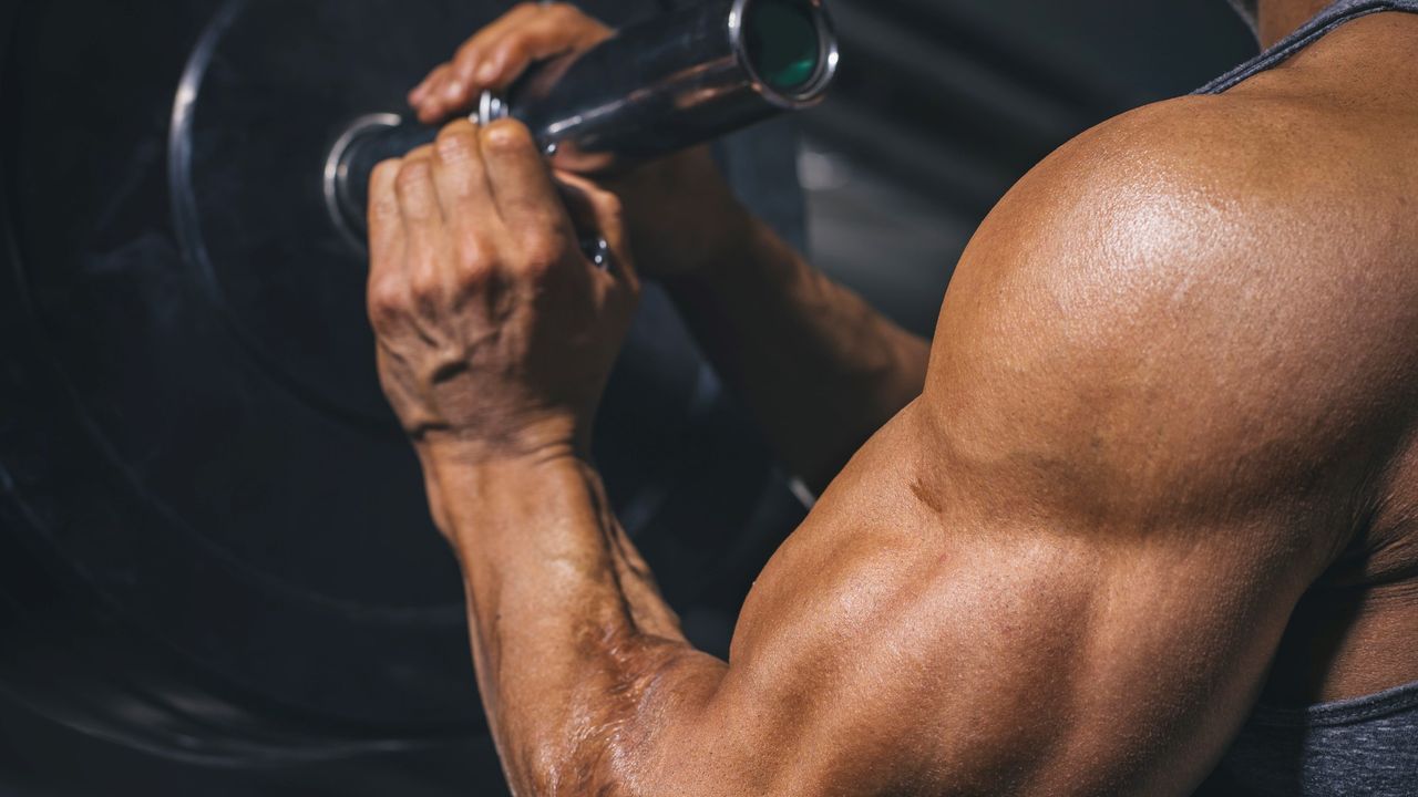 How to master upright rows: Bodybuilder secures a barbell collar on a barbell in a gym