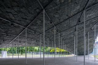 Inside view of Serpentine Pavilion 2019 made of metal poles holding up metal grids with slate roof