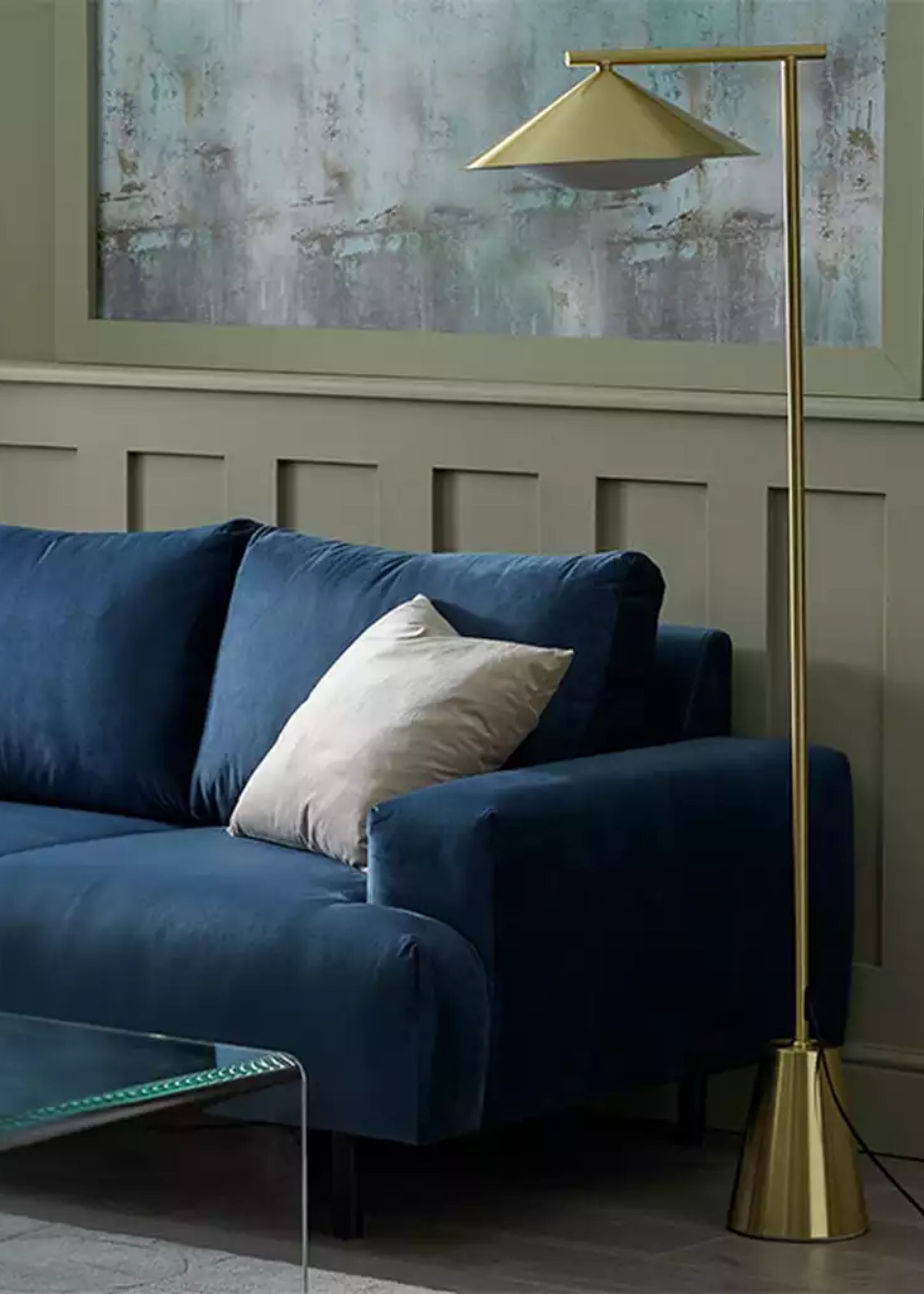 A blue sofa in an olive green living room with a gold/ brass floor lamp