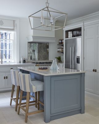 Kitchen with blue island and white cabinets and glass pendant light