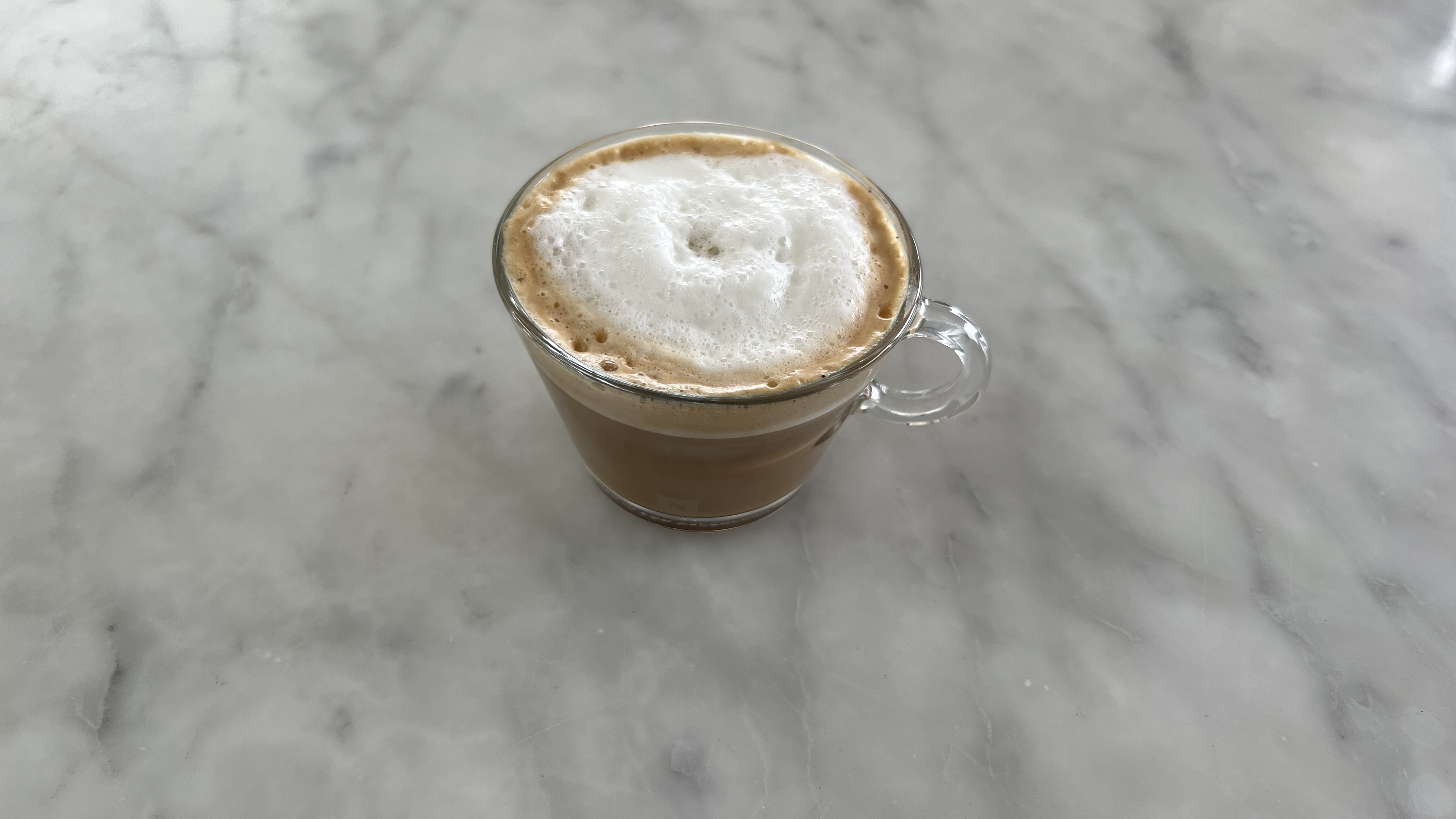 a foamy cut of latte on a marble worktop