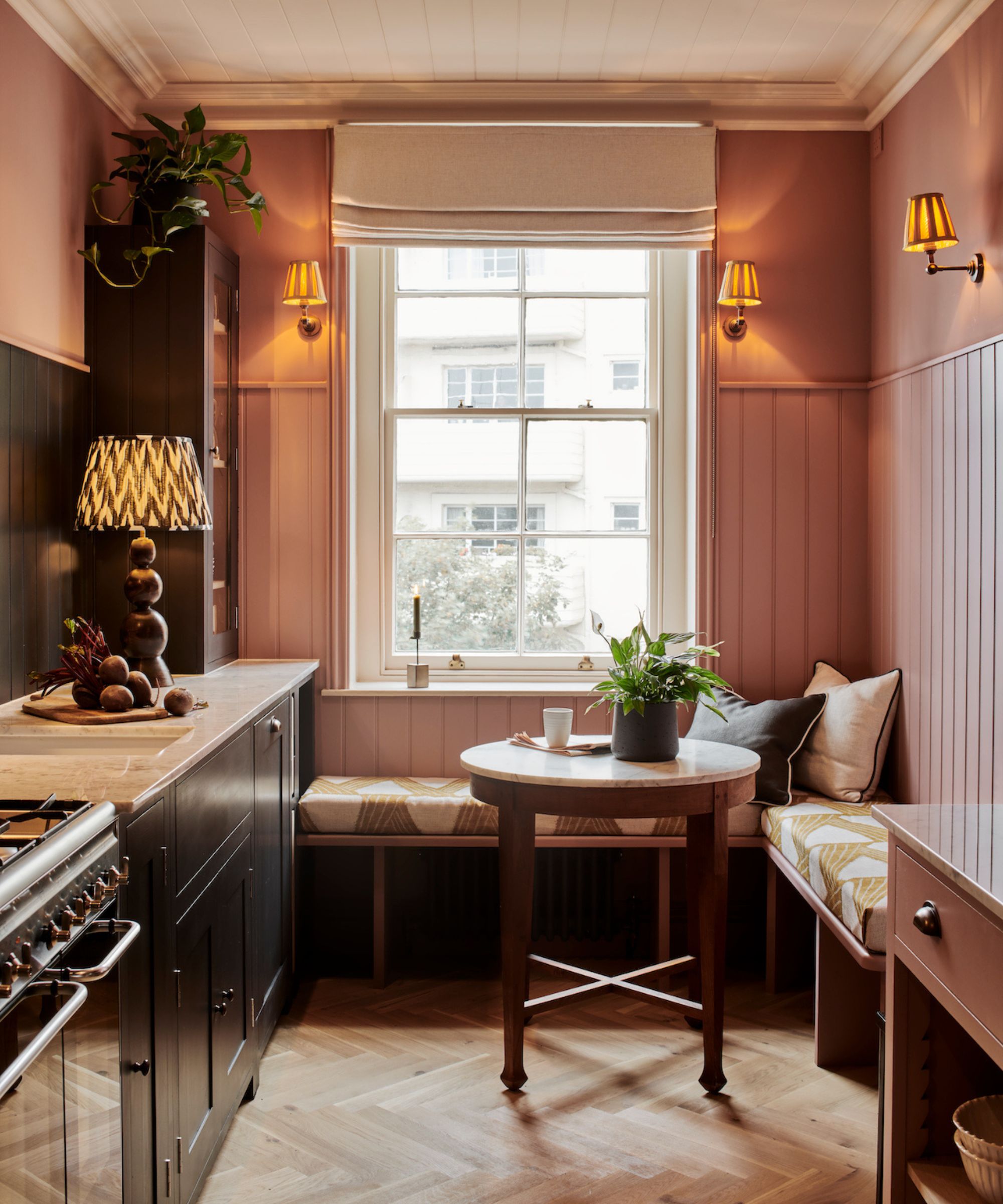 A pink kitchen banquette with cushions and soft lighting