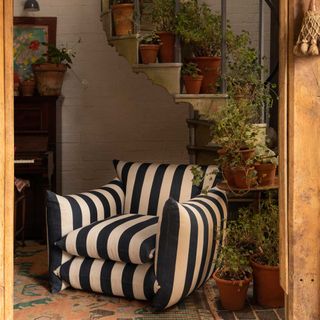 Black and white stiped couch with plants on a staircase and rustic accessories