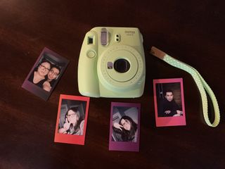 Green Fujifilm Instax Mini 9 on wood table with printed photos