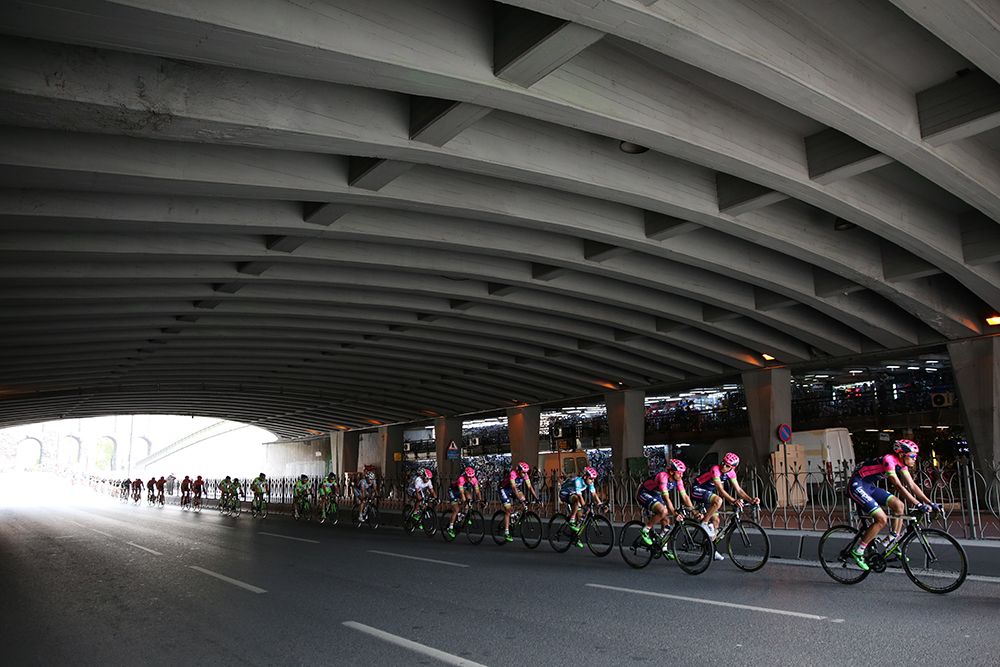 The peloton passes under a bridge