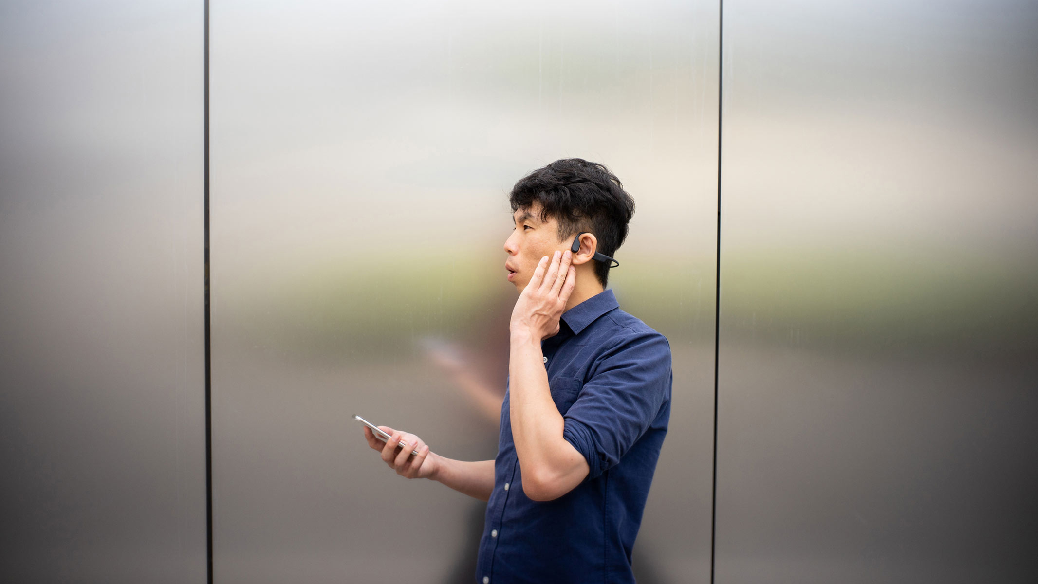 A man listening to bone conduction headphones in an elevator