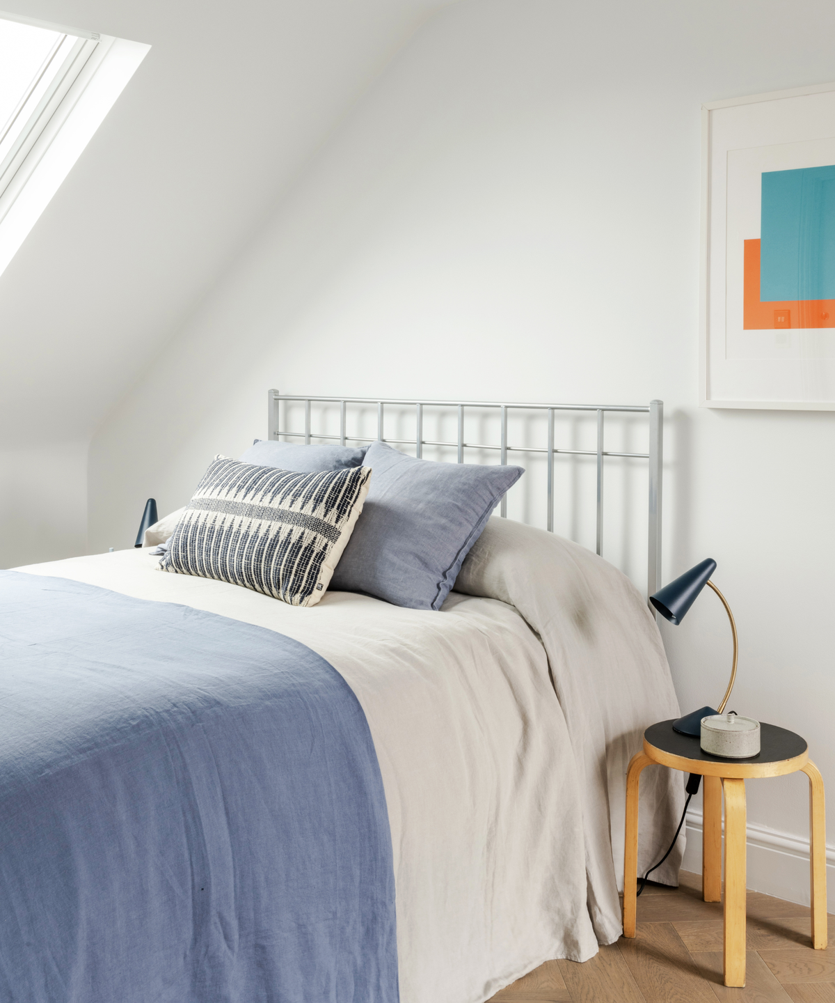 bed with blue and white sheets and bedside stool beside it