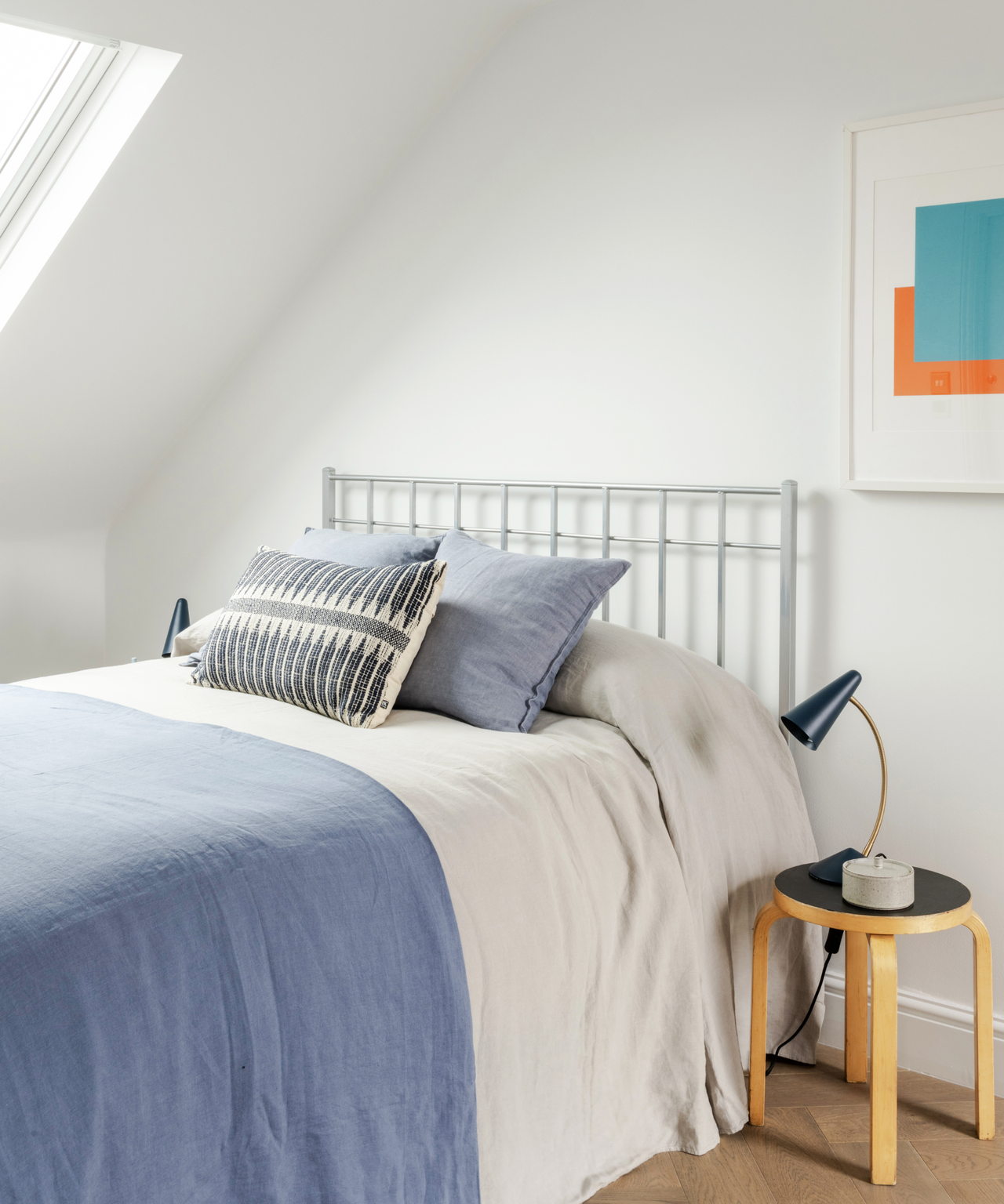 bed with blue and white sheets and bedside stool beside it
