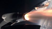 a space plane lights its rocket motor in space, with the curve of earth in the background.