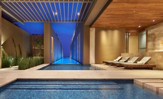 Los Cabos indoor pool with wooden ceilings, indoor plants and sand colored walls and paving