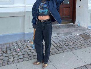 Woman in low-rise black jeans wearing ankle boots and a bomber jacket in NYC