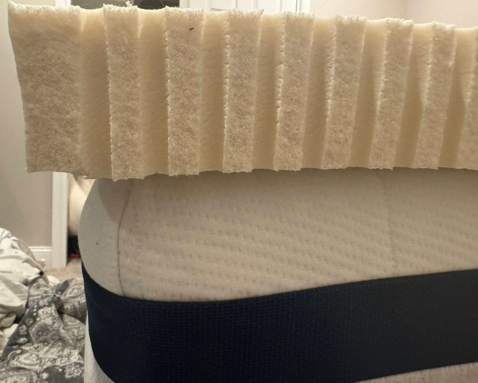 The Turmerry Latex Mattress Topper shown on a white mattress topper with a dark navy band.