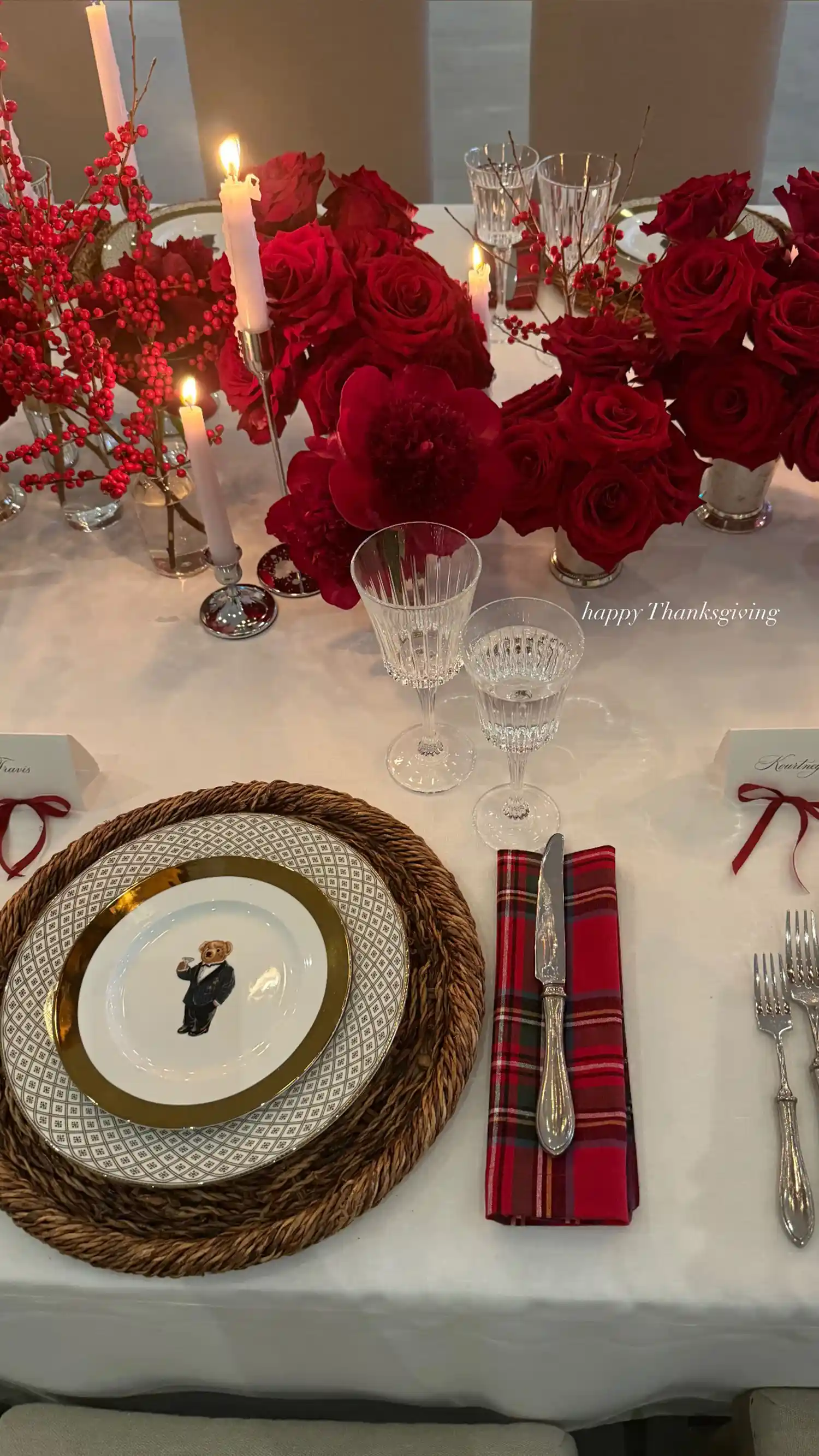 A fancy set table with candles and red flowers in middle