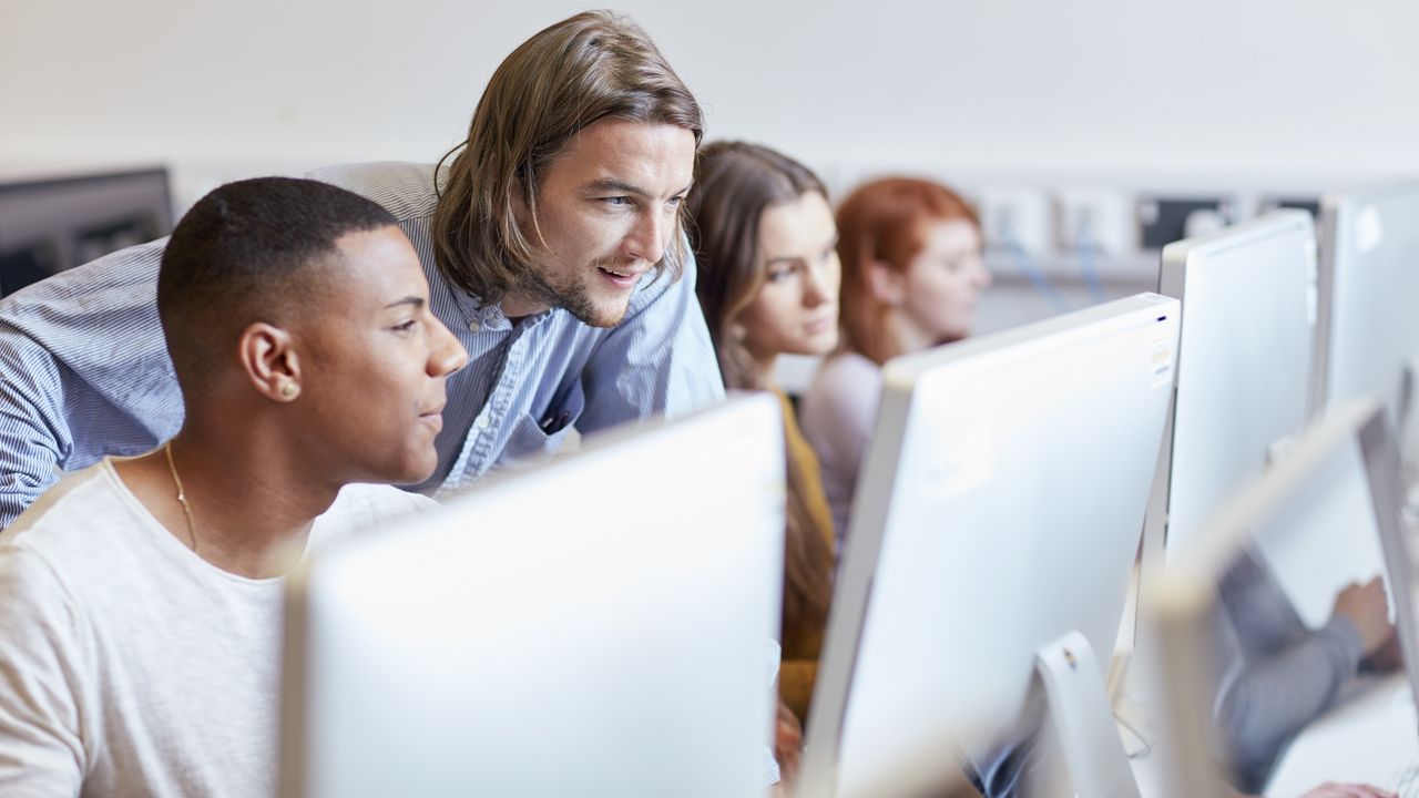 Four college students works on computers in a computer lab.