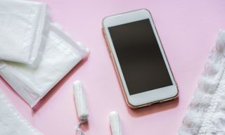 pads and tampons with a phone on a pink background