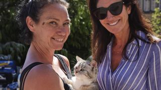Animal handler Lucy Smith and producer Yvonne Francas cuddle Humbug the cat on the set of All Creatures Great and Small.