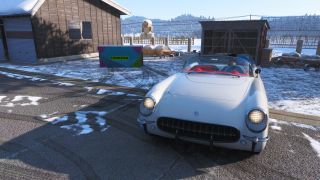 Forza Horizon 6 Hokubu Treasure Hunt: A front-on view of a white classic car parked next to a treasure chest outside a wooden building in a snowy field.