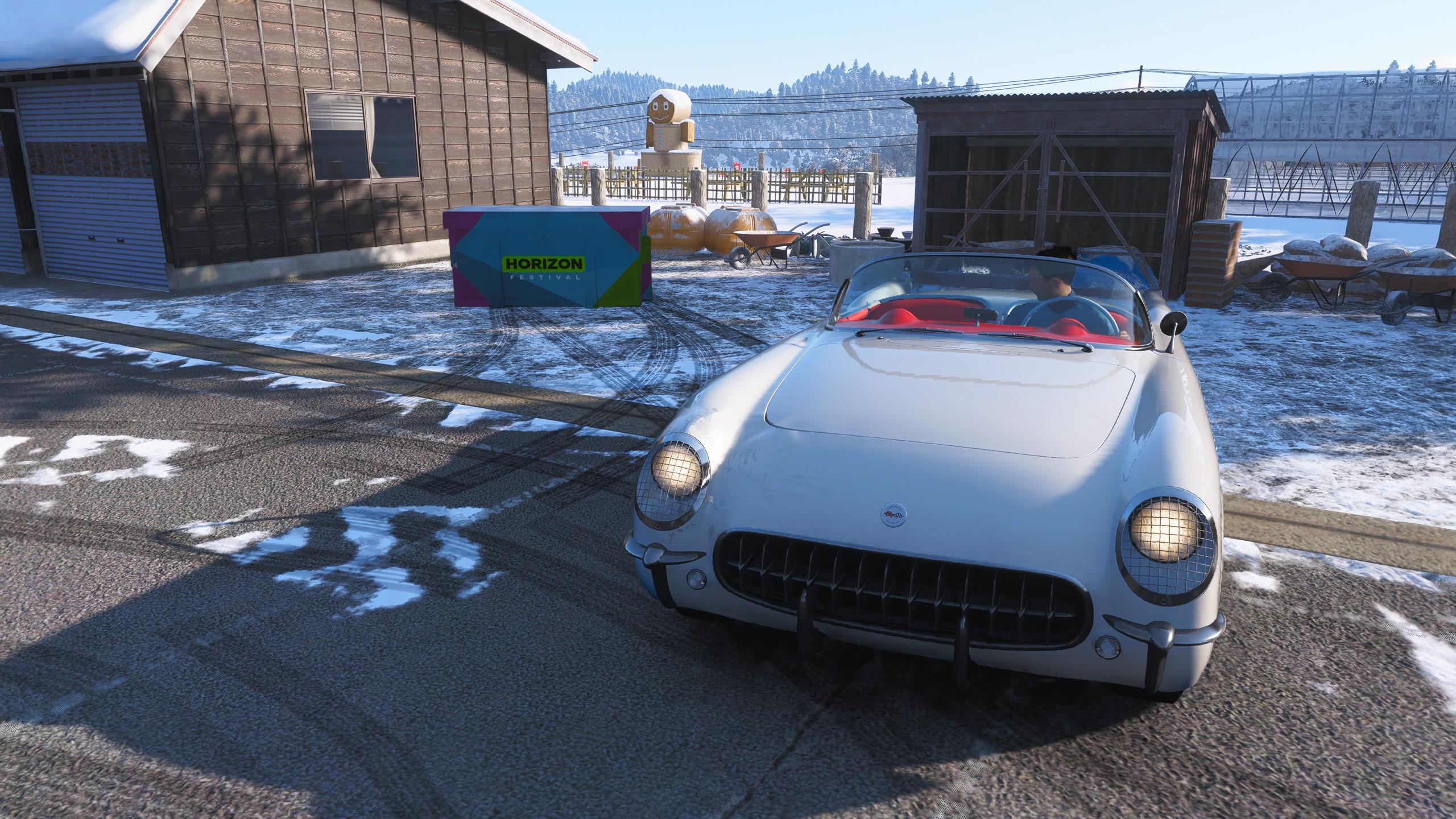 Forza Horizon 6 Hokubu Treasure Hunt: A front-on view of a white classic car parked next to a treasure chest outside a wooden building in a snowy field.
