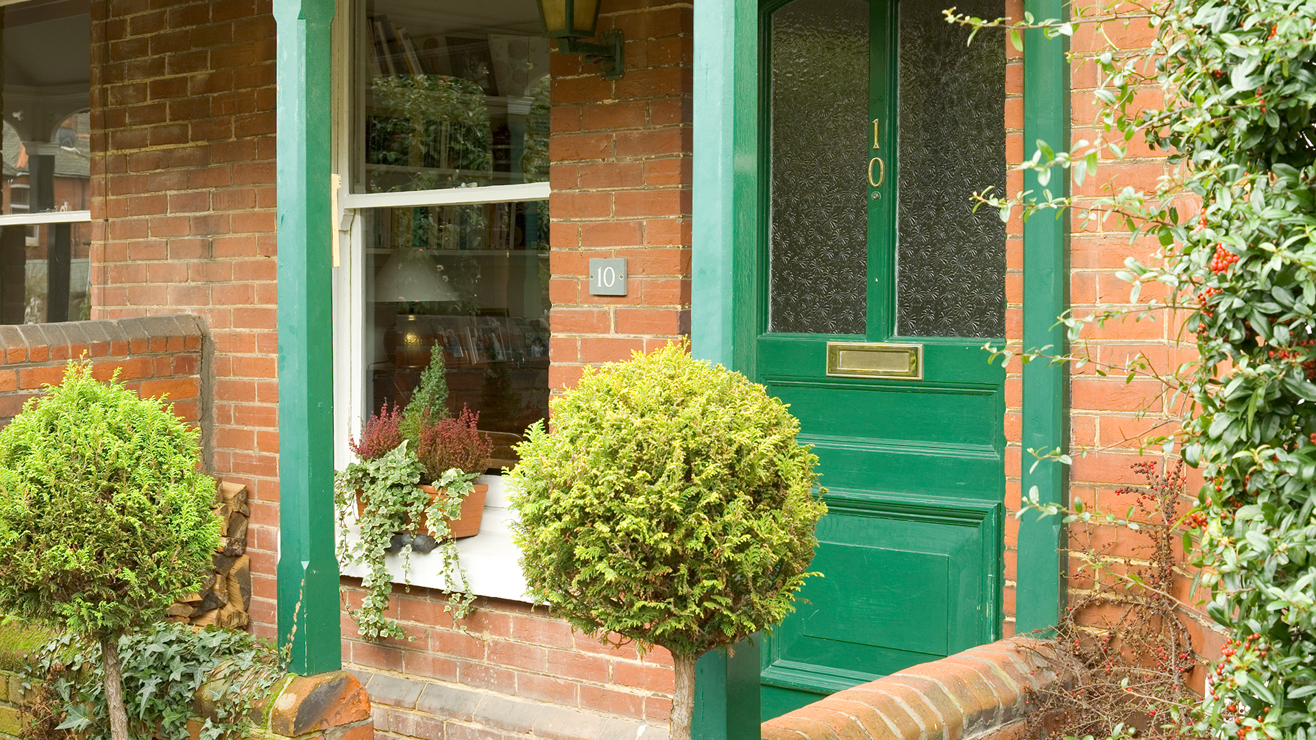 Exterior of a brick house with a green painted wooden front door