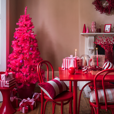 Hot pink christmas tree surrounded by red and pinked wrapped presents and red dining table