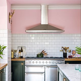 Open plan kitchen with pink walls, black Shaker style kitchen units, and rustic vintage furniture