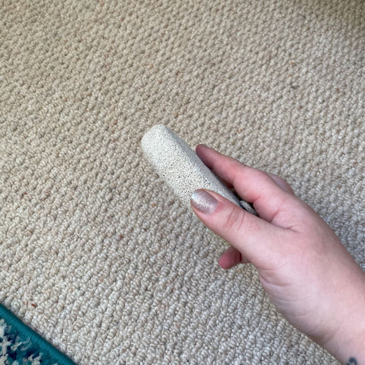 Holding a pumice stone just in front of cream carpet