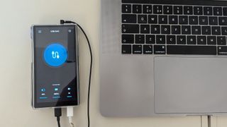 Fiio M23 portable music player plugged into Macbook on white table