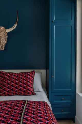 A bedroom with red bedding and blue walls