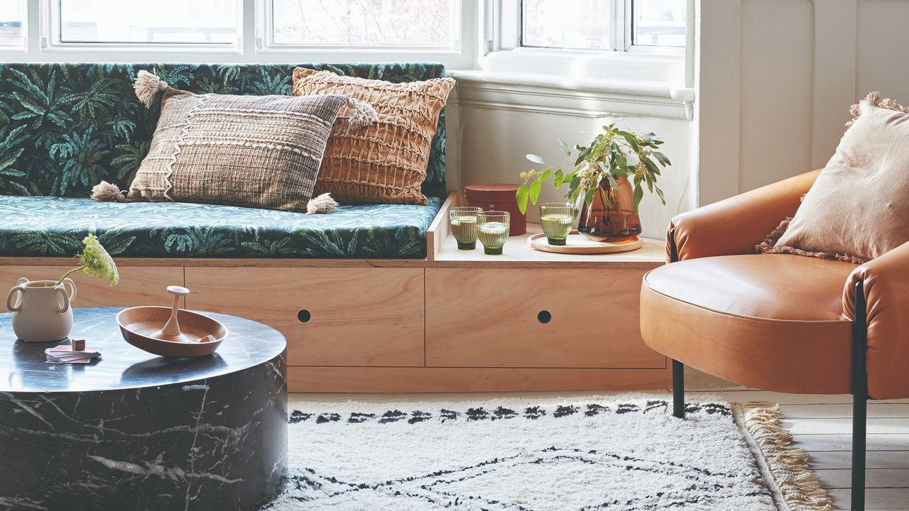 A living room with large bay windows, a marble coffee table and a leather chair