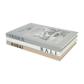 Three neutral coffee table books titled Venice, Bali, and Dubai stacked on top of each other