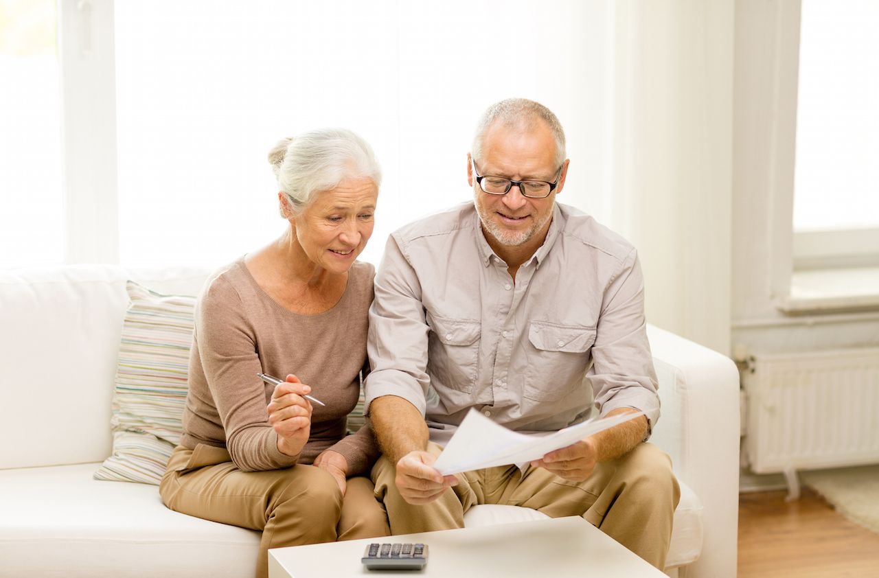 family, business, savings, age and people concept - smiling senior couple with papers and calculator at home