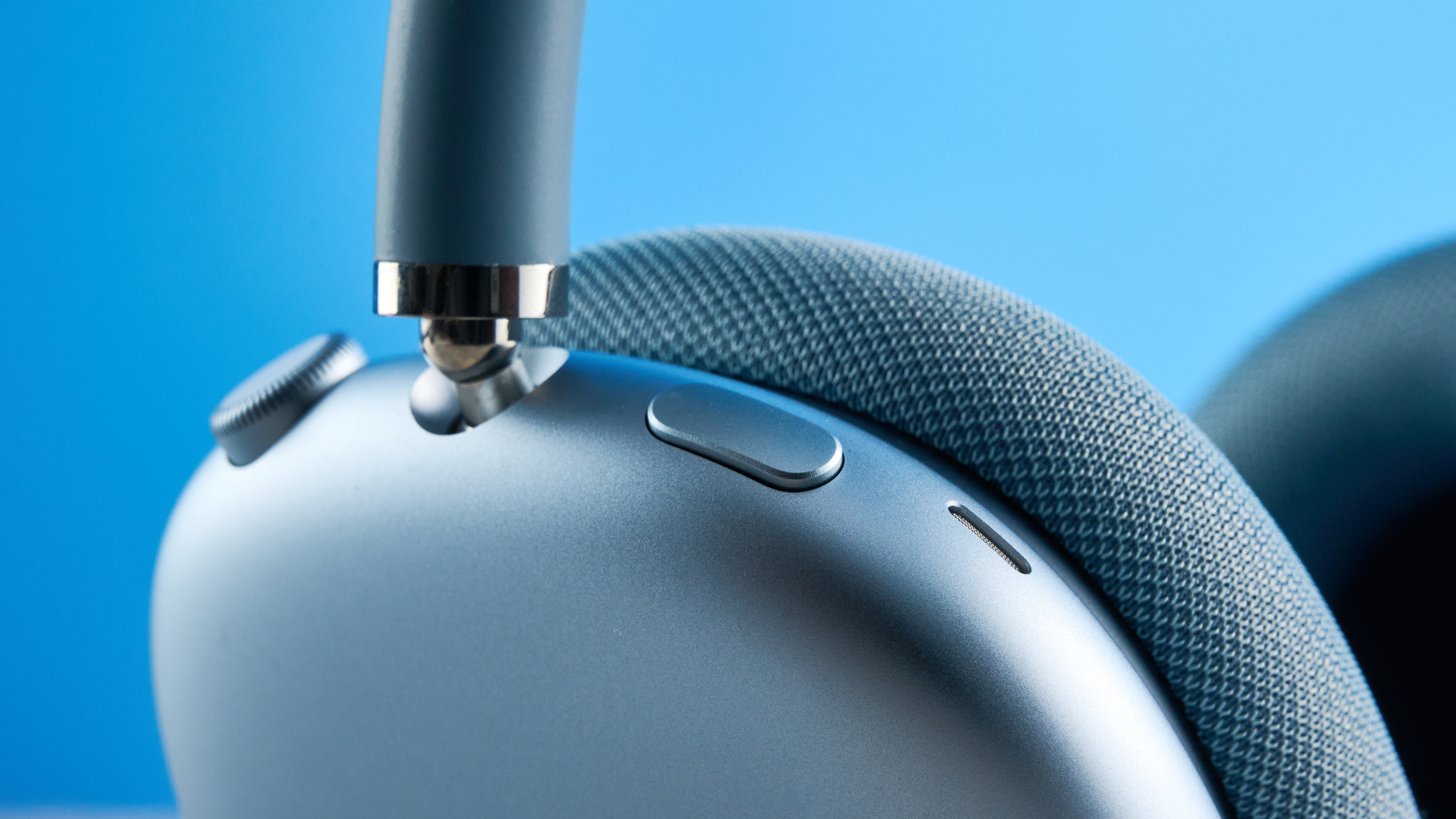 the apple airpods max 2 in blue photographed against a blue tom's guide background, showing the mesh headband, anodized aluminum ear cups, carry case, and controls