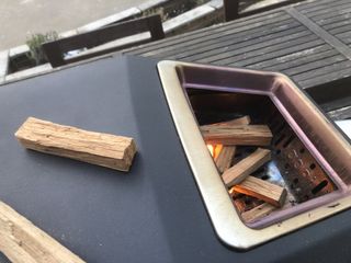 Adding wood to the fuel hatch at the back of the Ooni Karu 16 to help get up to temperature