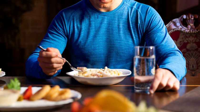 A photo of a man wearing gym kit eating pasta 