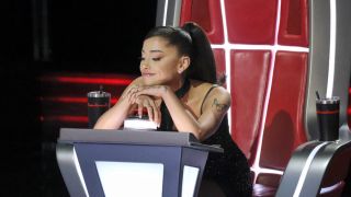 Ariana Grande leaning on her button on The Voice