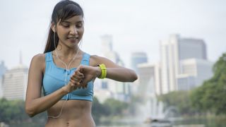 How accurate are fitness trackers: Image shows woman runner looking at fitness tracker