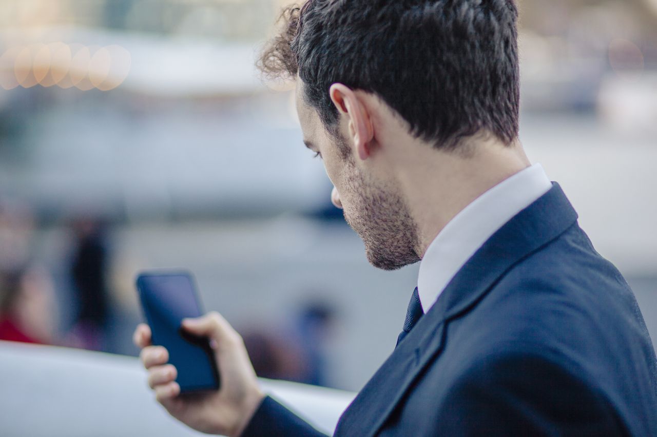 Over the shoulder view of businessman texting on smartphone