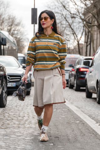 woman wearing rugby shirt, skirt, and sneakers