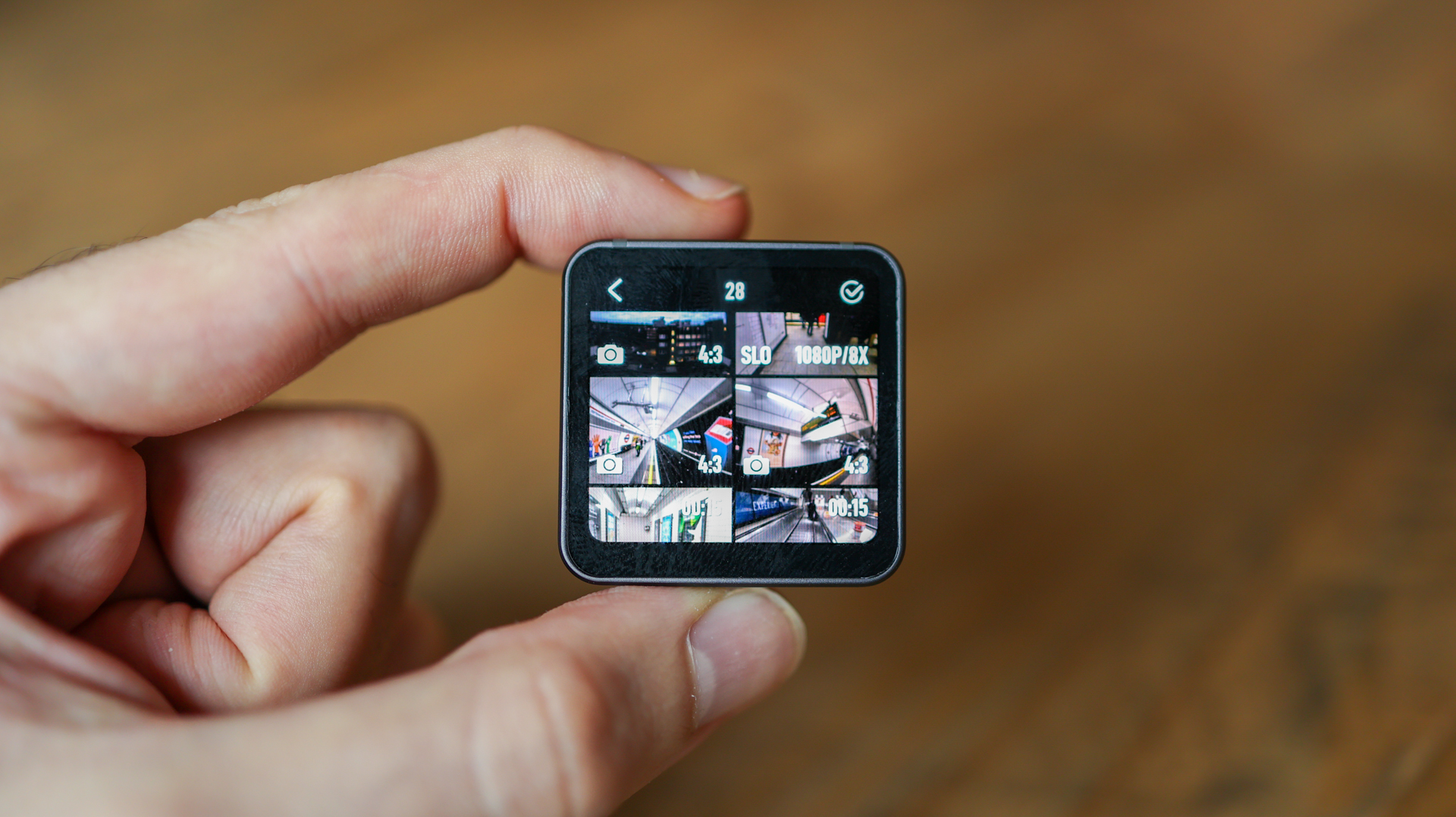 A hand holding the DJI Action 2 action camera showing its rear screen