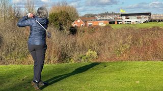 Female golfer hitting a hybrid