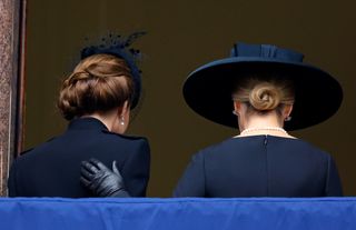 Back view of Kate Middleton and Duchess Sophie wearing black coats and hats with Sophie's hand on Kate's back during Remembrance Day 2024