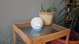 the amazon echo dot with clock pictured on a glass table