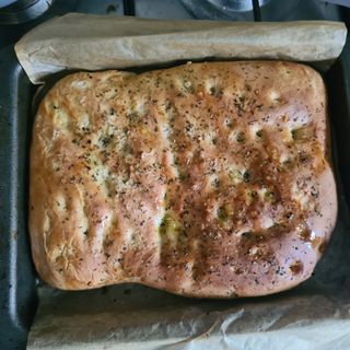 Baked brown bread in bread pan with herbs on