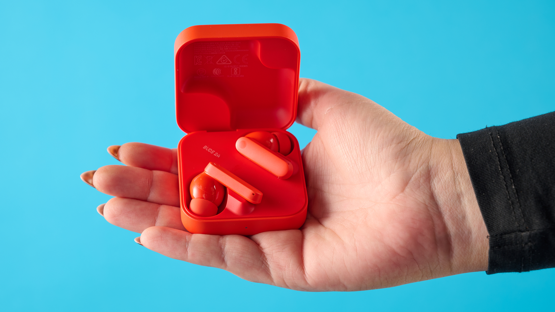 cmf buds 2a in the orange colorway photographed in front of a blue background