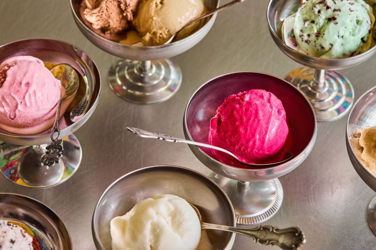 A series of retro-inspired silver ice cream cups and wine glasses are showcased within an ice cream parlor.