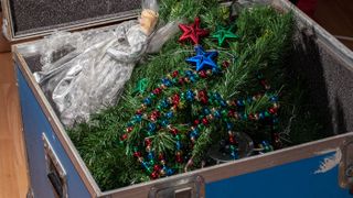 A Christmas tree being stored in a trunk with decorations